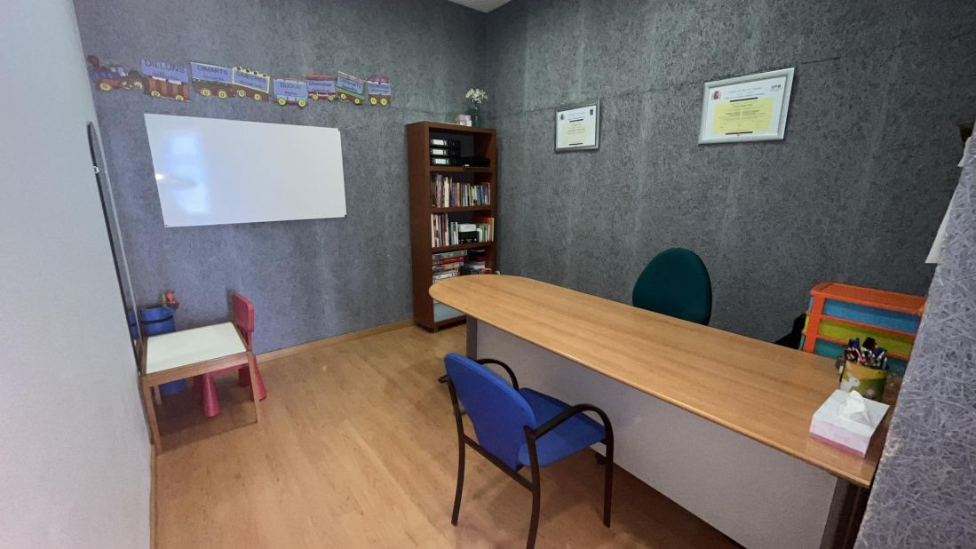 Imagen de sala de entrada con mesa larga, dos sillas enfrentadas y una mesa infantil en la esquina
