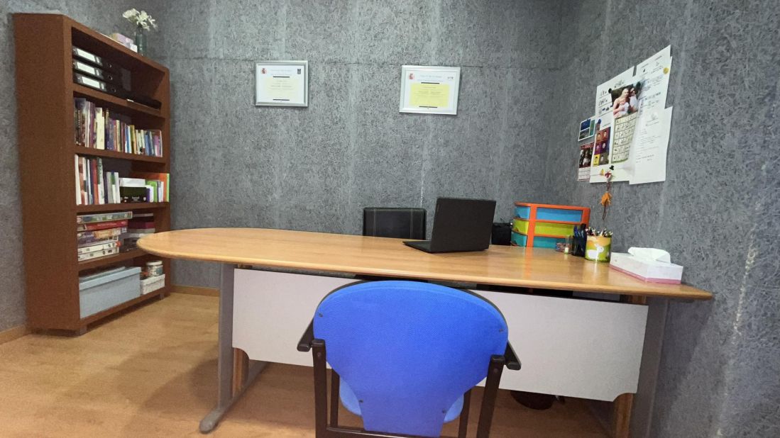 Detalle de interior de sala con mesa, dos sillas enfrentadas y estantería a la izquierda