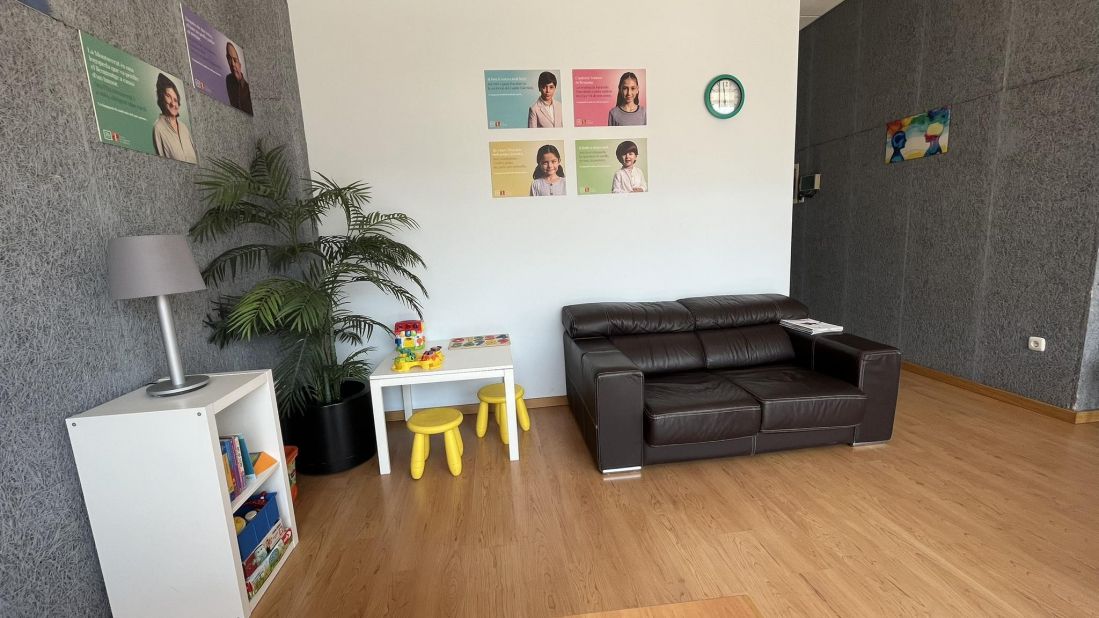 Detalle de sala de espera con sofá marrón grande y rincón de mesa y juegos infantiles