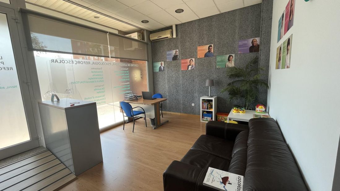 Foto del interior de una sala de recepción con un sofá, mesa con dos sillas y mesa infantil con juegos en la esquina